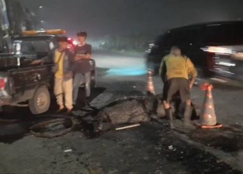 Petugas Dinas PU dan Tata Ruang Provinsi Banten membersihkan tumpukan hotmix di Jalan Pondok Cabe.(red)